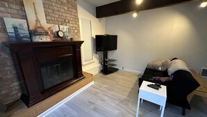 Ein Wohnzimmer mit Kamin, Fernseher, einer Couch und einem kleinen Tisch.