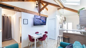 A modern living space with a dining area, kitchen, and a large window.