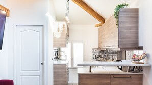 A modern kitchen with wooden cabinets, a white countertop, and two stools.