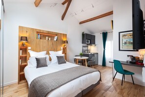 Een moderne hotelkamer met een groot bed, een bureau en een kitchenette.