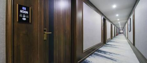 A hotel corridor with wooden doors, a carpeted floor, and a sign indicating room number 8568.