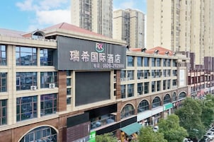 Un edificio de hotel con varios pisos, amplias ventanas y un cartel llamativo.