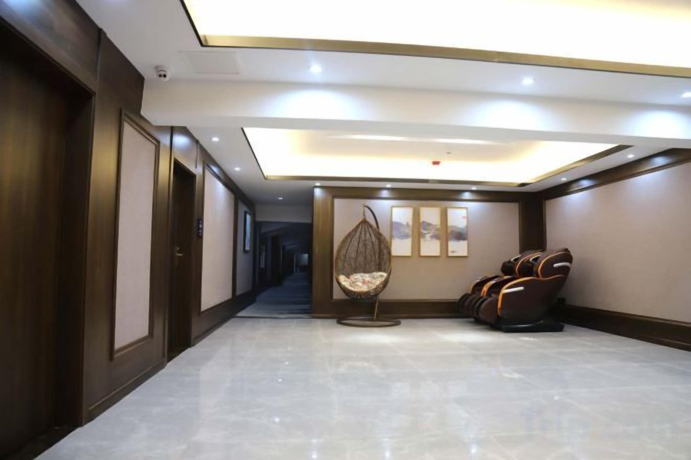 A hotel corridor with a seating area, including a hanging chair and massage chairs.