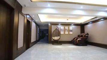 A hotel corridor with a seating area, including a hanging chair and massage chairs.