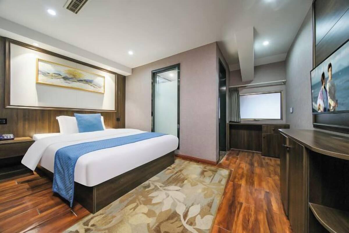 Une chambre d’hôtel moderne avec un grand lit, une télévision, un bureau et un tableau au mur.