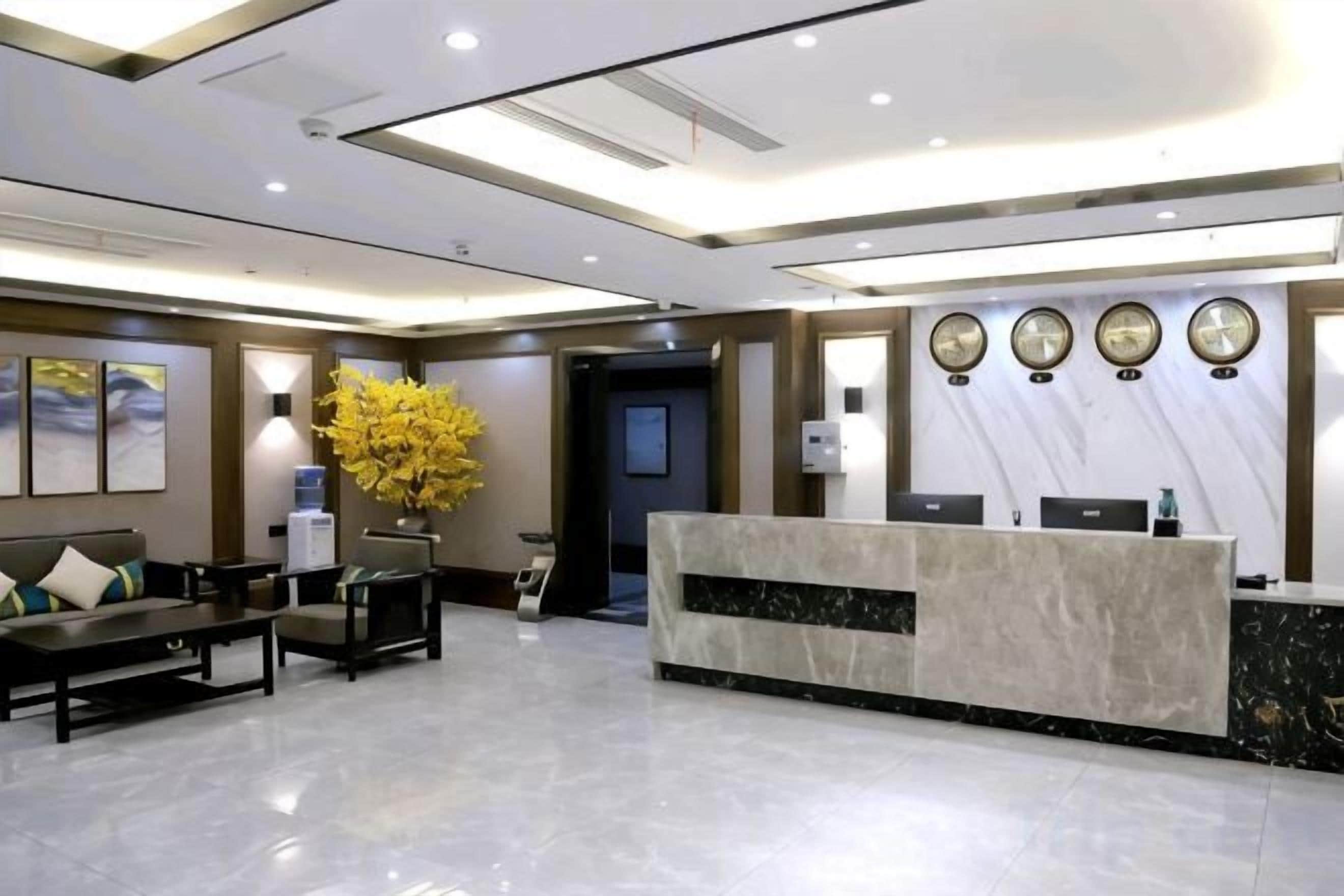 A hotel reception area with a marble reception desk, seating area, and wall-mounted clocks.