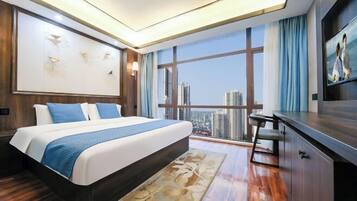 A modern hotel room with a large bed, a desk, and a view of the cityscape.