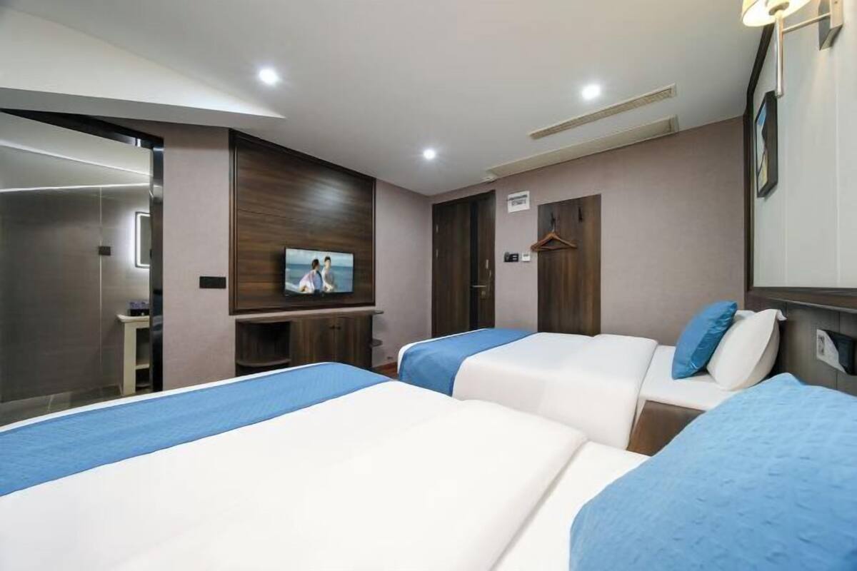 Une chambre d’hôtel avec deux lits, une télévision, un miroir et une armoire en bois.
