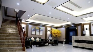 A modern lobby with a marble staircase, a reception desk, and a seating area with a large yellow flower arrangement. - Ruixi International Hotel (Guang'an Railway Station Branch) (Guang'an)