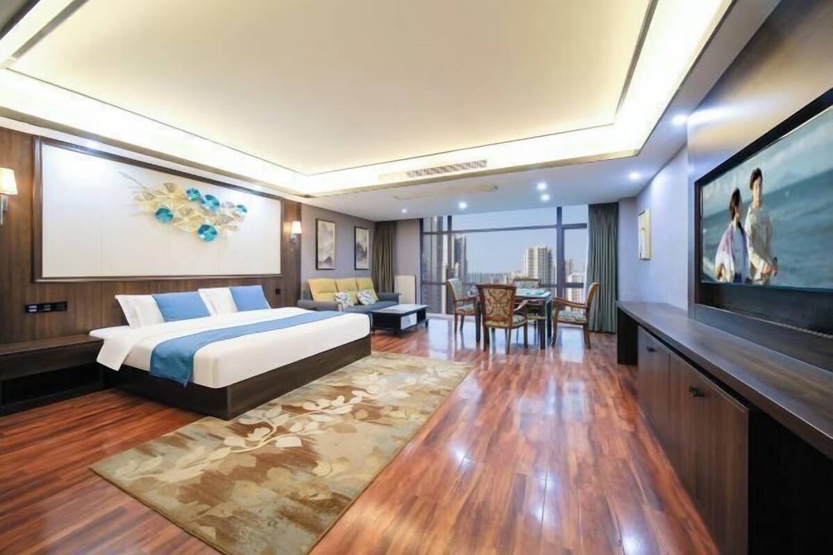 Une chambre d’hôtel moderne dotée d’un grand lit, d’un coin repas et offrant une vue sur la ville.