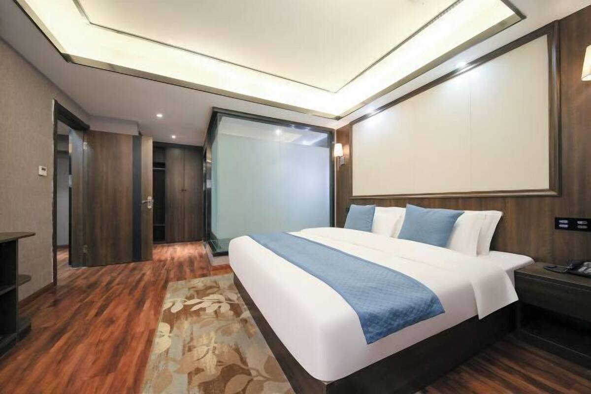 Une chambre d’hôtel moderne dotée d’un grand lit, d’un bureau et d’une cloison en verre.