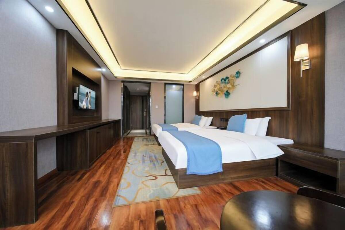 Une chambre d’hôtel avec un grand lit, une télévision, un bureau et une lampe fixée au mur.