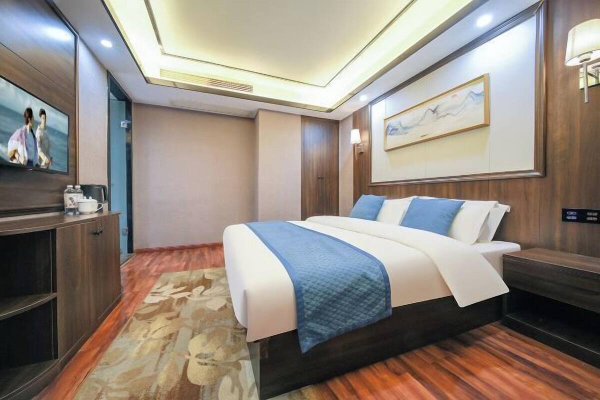 Une chambre d’hôtel moderne dotée d’un grand lit, d’une télévision à écran plat, d’une table de chevet et d’une œuvre d’art accrochée au mur.