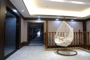 A hallway with a hanging chair, a staircase, and a wooden railing. - Ruixi International Hotel (Guang'an Railway Station Branch) (Guang'an)