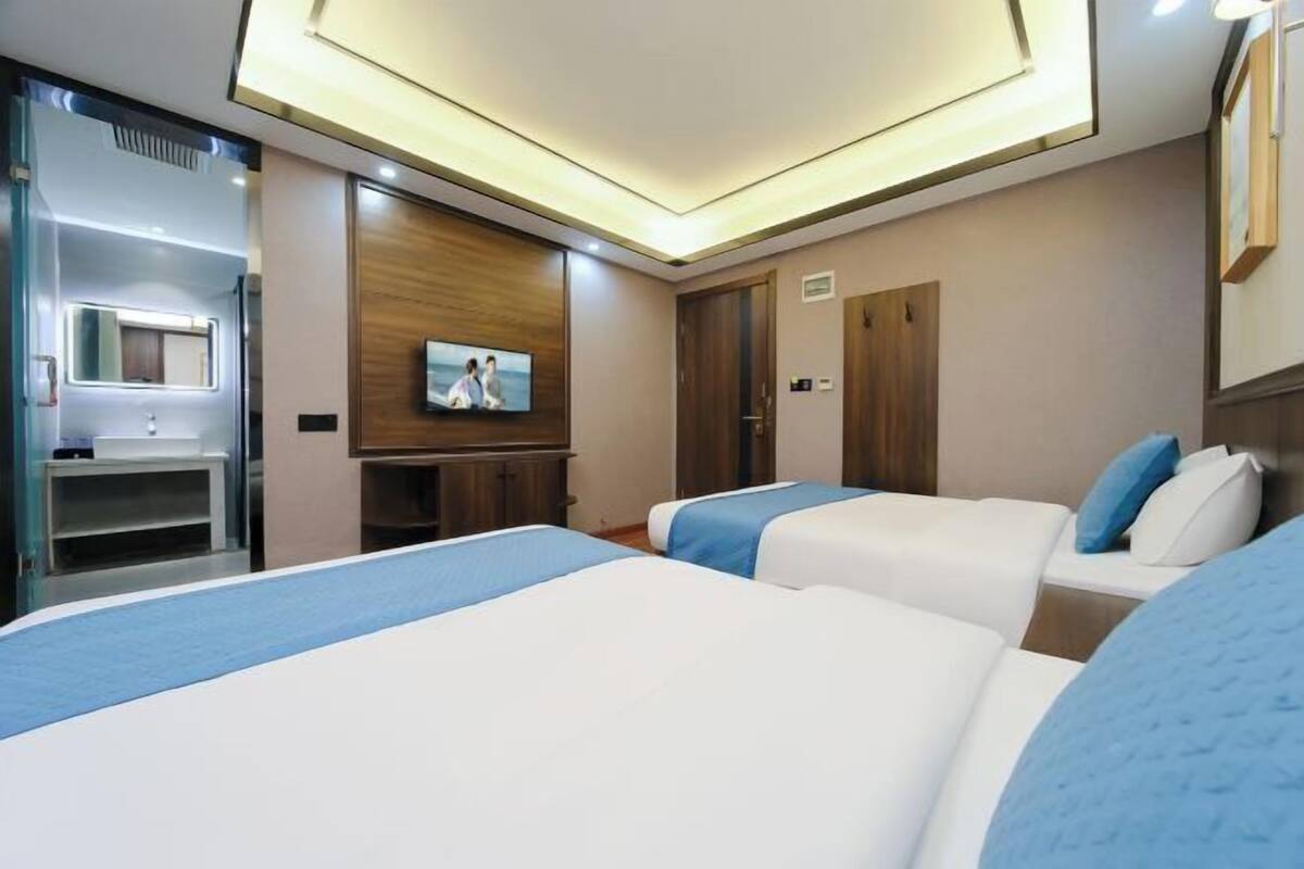 Une chambre d’hôtel avec deux lits, une télévision, un miroir et une armoire en bois.
