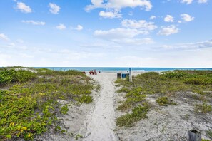 A sandy beach path leading to a small structure with a view of the ocean.