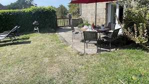 Une terrasse avec une table et des chaises, un parasol rouge et un barbecue.