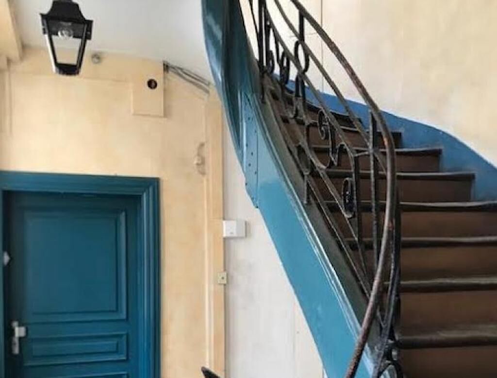 Eine Treppe mit blauer Handlauf und einer Tür mit blauem Rahmen.