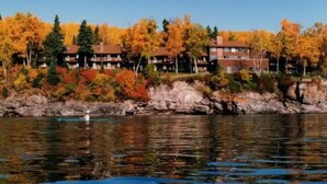 A lakeside view with autumn foliage and a row of multi-story buildings. - Cedar’s Seaside Chalet (Tofte)