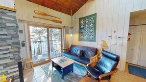 A cozy living room with a blue sofa, wooden coffee table, and a fireplace. - Cedar’s Seaside Chalet (Tofte)
