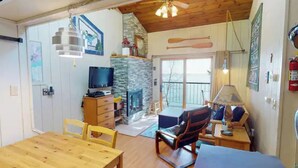 A cozy living room with a fireplace, wooden furniture, and a television. - Cedar’s Seaside Chalet (Tofte)