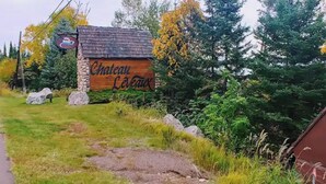 A rustic building with a sign reading "Chateau LeVeaux" surrounded by trees and rocks. - Cedar’s Seaside Chalet (Tofte)