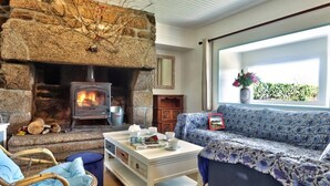 A cozy living room with a stone fireplace, a sofa, and a coffee table. - Gîte 4 people -  2 swimming pools (1 with telescopic dome) - The beach on foot (Trégunc)