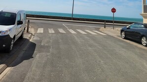 Eine Küstenstraße mit einem Stoppschild, einem weißen Lieferwagen und einem schwarzen Auto, das am Straßenrand geparkt ist.