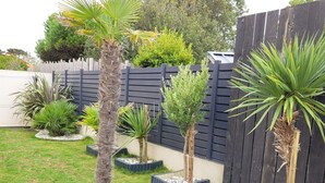 Ein Garten mit Whirlpool, verschiedenen Blumentöpfen und einem Holzzaun.