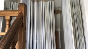 Un escalier avec des rampes en bois et un rideau à rayures.