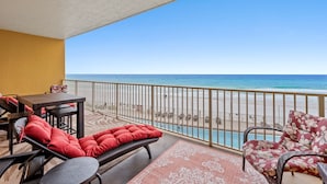 Un balcón con mobiliario de mimbre, una piscina y vista a la playa.