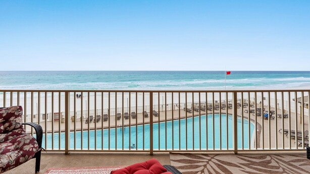 Un balcón con vista a una playa y una piscina.