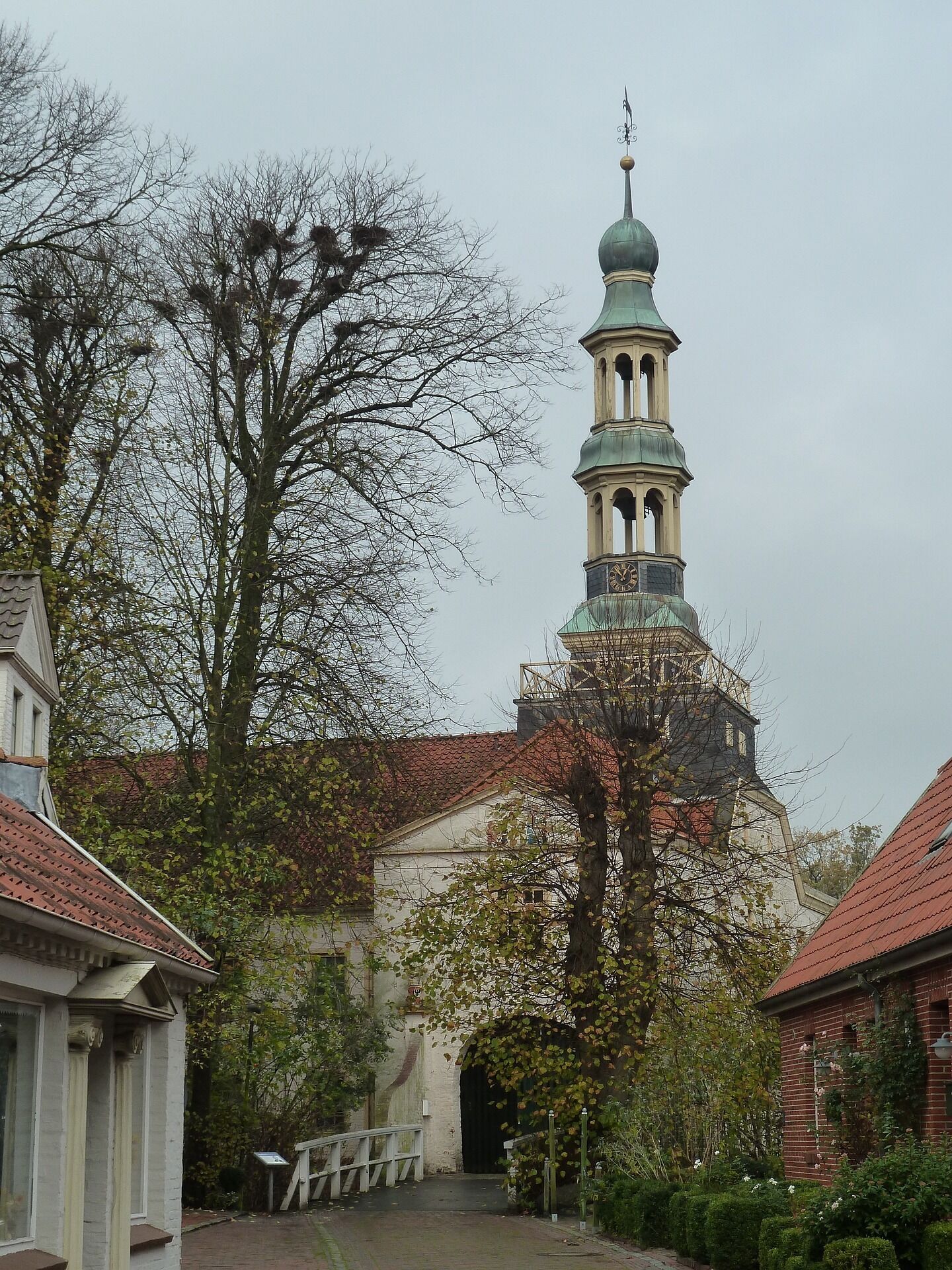 A historic building with a prominent tower featuring a clock and a weather vane.