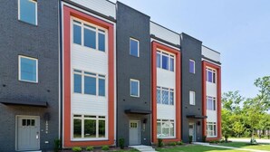 Un immeuble résidentiel moderne à plusieurs étages, doté d’une façade en briques, de grandes fenêtres et d’une pelouse bien entretenue.