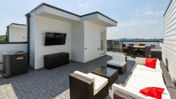 Une terrasse sur le toit avec des sièges extérieurs, un téléviseur à écran plat et un appareil de climatisation.