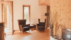 Un salón acogedor con suelo de madera, dos sillones, una mesita y una chimenea.