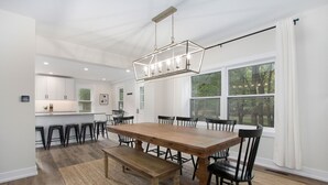 A spacious dining area with a large wooden table, black chairs, and a hanging light fixture. - Sleeps 10-Hot Tub-Close to Downtown-Resort Pool (Saugatuck Township)