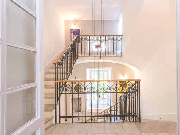 A multi-level interior with a staircase featuring ornate metal railings and a wooden handrail.