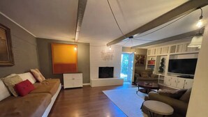 Ein modernes Wohnzimmer mit Kamin, einer Couch, einem Couchtisch und einem Fernseher.