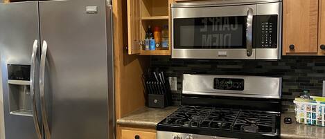 A kitchen with stainless steel appliances, wooden cabinets, and a built-in microwave.