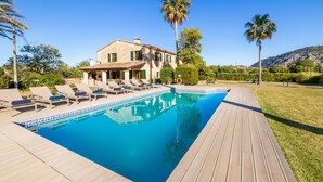 Une villa avec piscine, des chaises longues et une terrasse en bois.