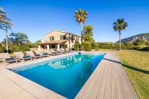Uma villa com piscina, espreguiçadeiras e um deck de madeira.