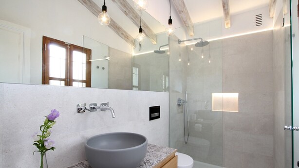 Une salle de bain moderne avec un grand miroir, un lavabo sur colonne, une douche et des toilettes.