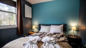 Habitación de hotel con una cama grande, dos lámparas de noche y una ventana con cortinas.