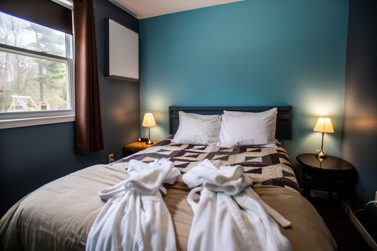 Habitación de hotel con una cama grande, dos lámparas de noche y una ventana con cortinas.