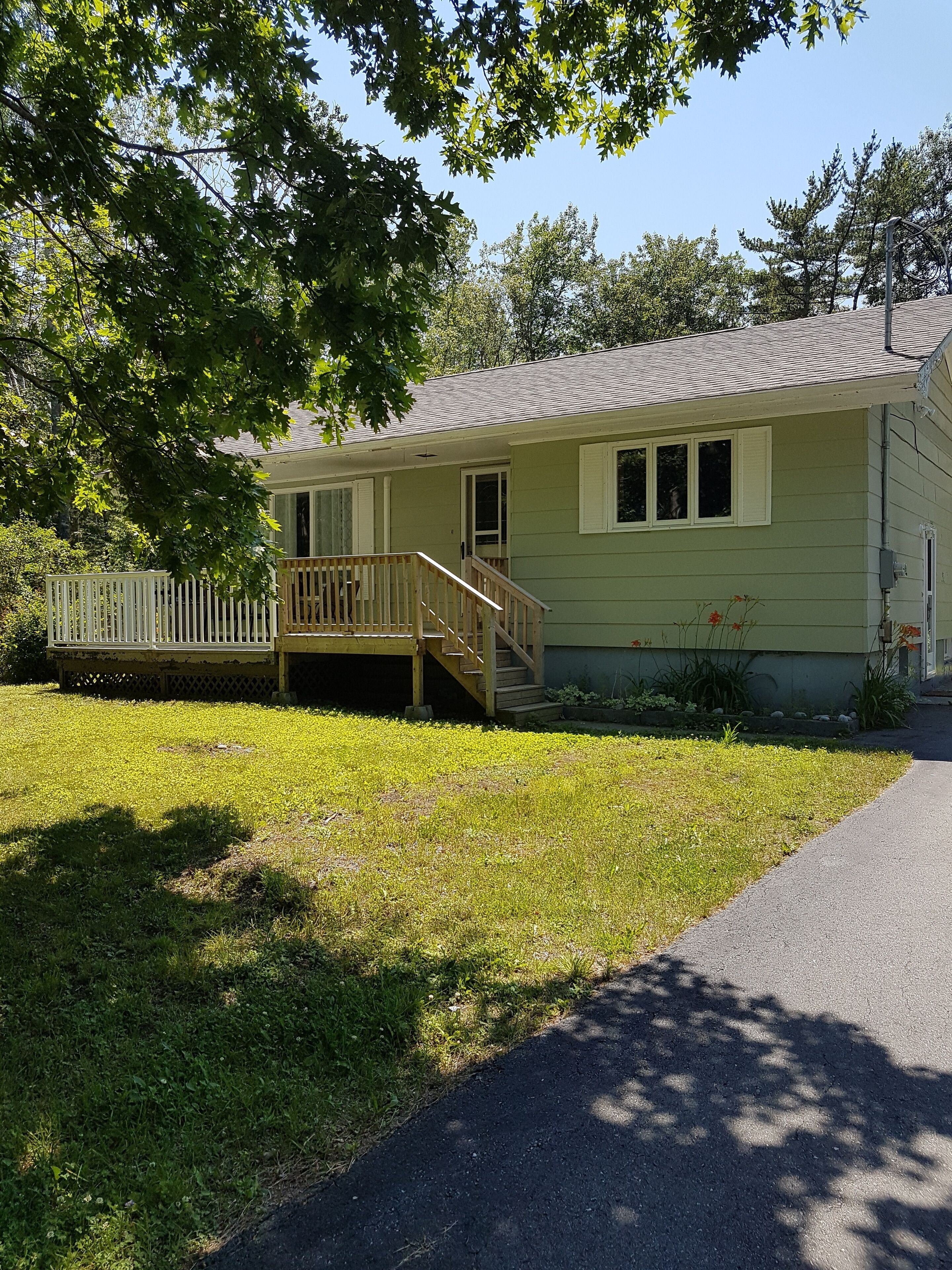 A single-story house with a front porch, a small deck, and a front yard.