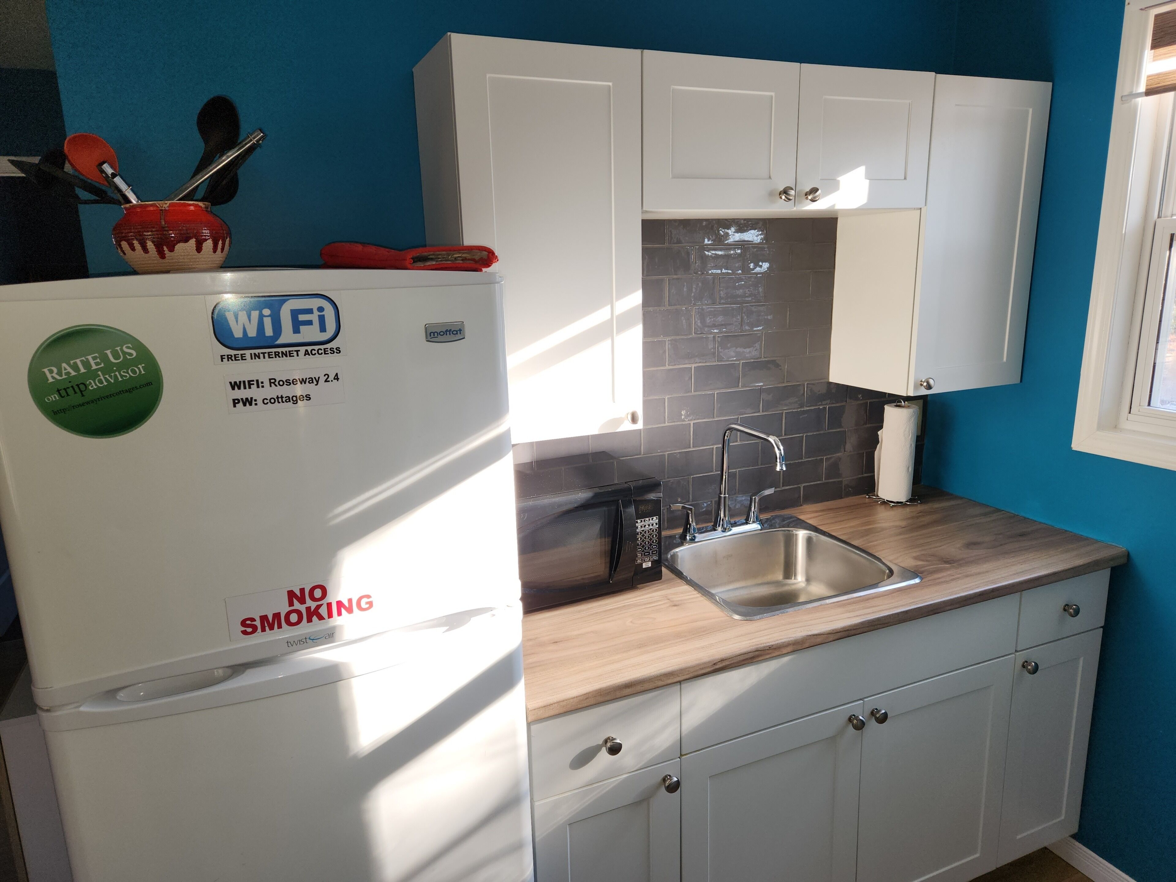 A kitchen with a white refrigerator, a microwave, a sink, and cabinets.