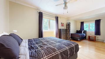 A bedroom with a bed, a dresser, a desk, and a window.