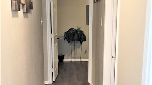 A hallway with wooden flooring, white trim, and a door leading to another room. - Super Cozy Home Away From Home (Abilene)