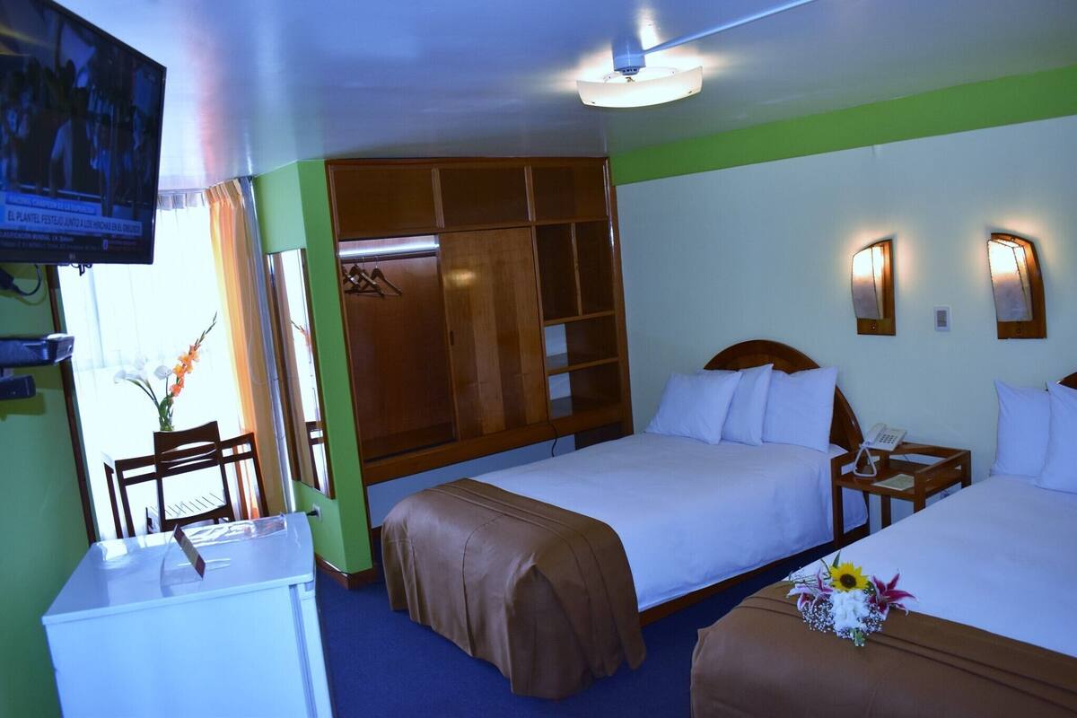 A hotel room with two beds, a desk, a television, and a wardrobe.